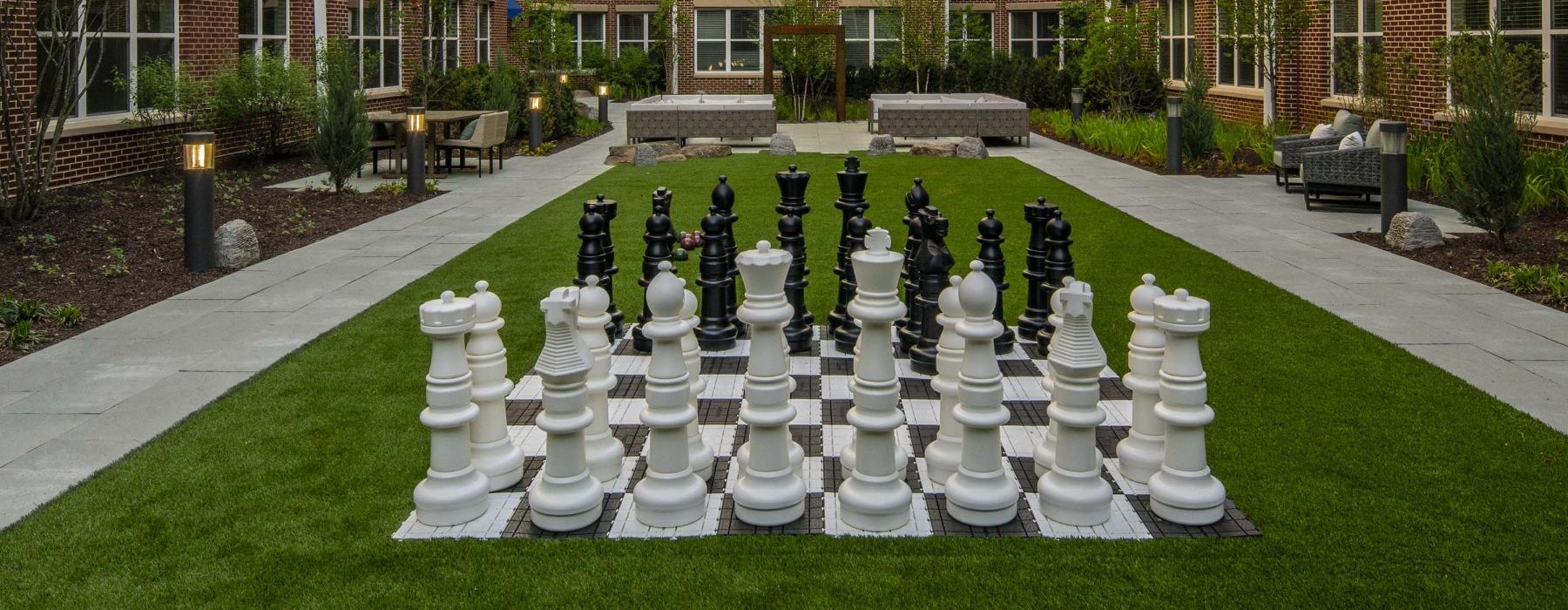 a courtyard with a large chess board and buildings